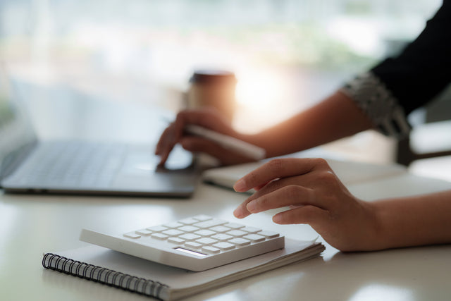Hands on a computer and a calculator on a desktop