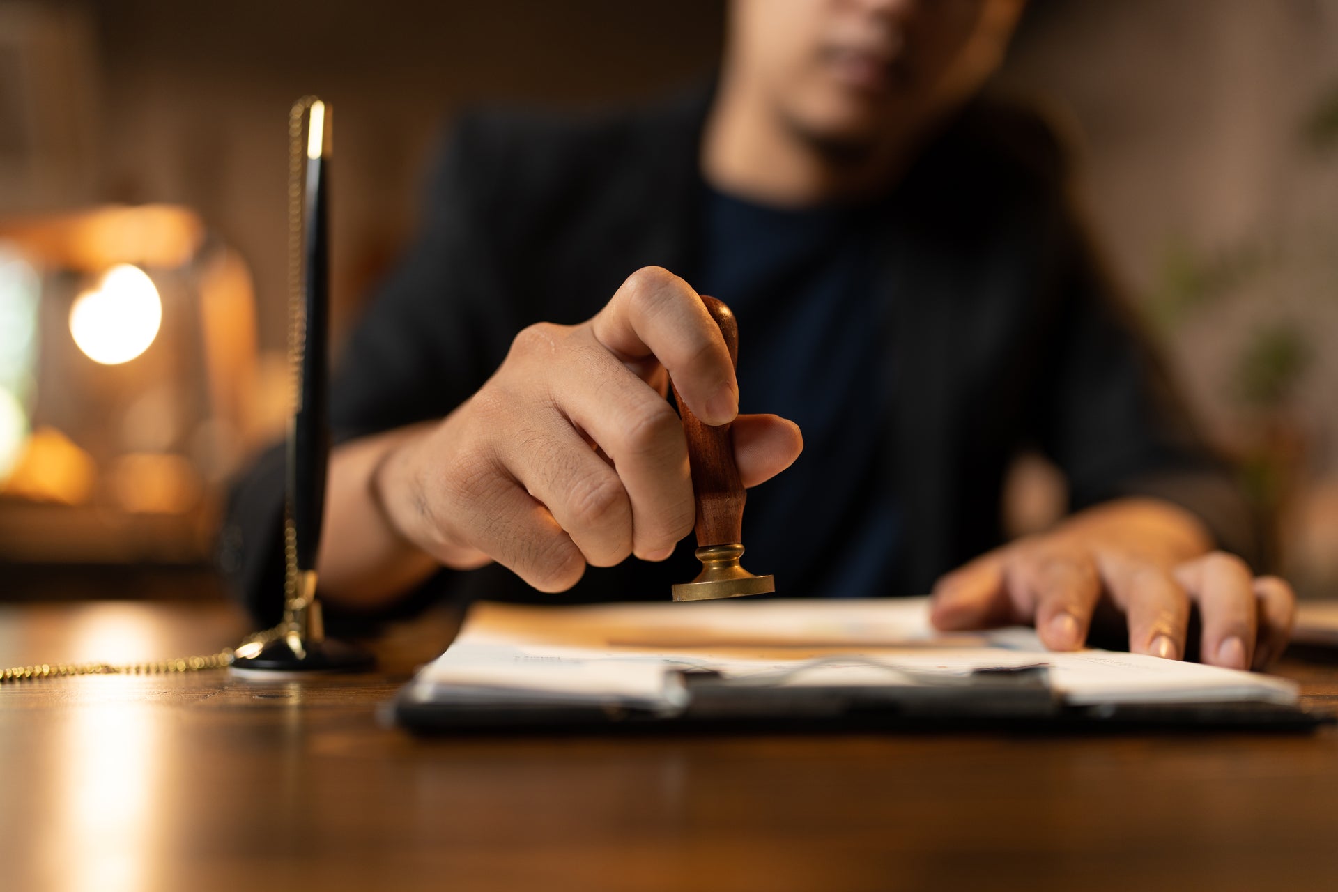 Notepad and pen with a hand preparing the stamp with notary seal