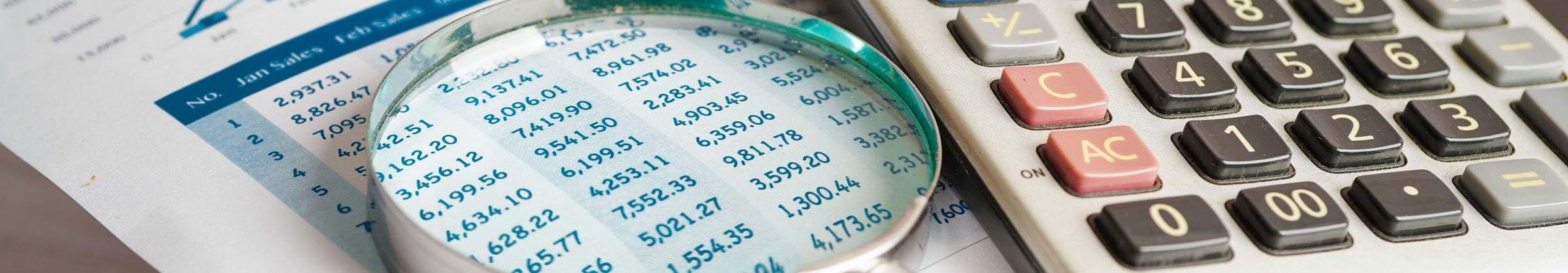 Magnifying glass on report of numbers next to calculator.